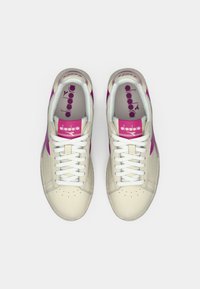 Beige sneakers with white laces, pink accents, and a logo. Smooth leather material and perforated toe detailing.