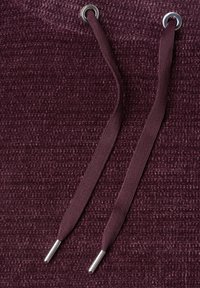 Tissu tricoté violet foncé avec deux cordons assortis passant à travers des œillets métalliques en haut.