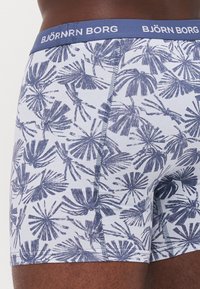Blå og hvite boxershorts med palmebladmønster. Myk, stretchaktig stoff; elastisk linning med "BJÖRN BORG" logo. Glatt, tettsittende design.