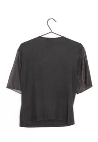 Svart kortärmad topp med en solid tygkropp och genomskinliga meshärmar. Sömmen är något rundad med en avslappnad passform.