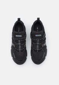 Chaussures de sport noires avec une tige en mesh, une semelle en caoutchouc, des accents réfléchissants et un talon texturé, conçues pour le confort et le soutien.