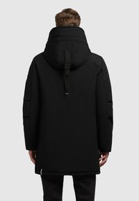 Sort parka jakke med høj krave og justerbar hætte, der har en stropdetalje bagpå og et slankt, isoleret design.