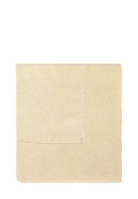 Beige gebreide deken met een geprofileerd patroon aan de ene kant en een gladde oppervlakte aan de andere kant, met een klein logo-accent in de hoek.