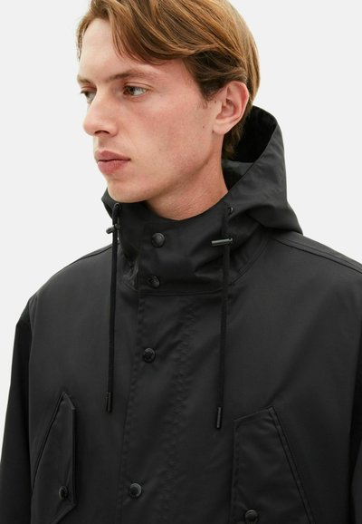 Schwarze wasserdichte Jacke mit hohem Kragen, verstellbarem Zugband, Druckknöpfen und großen Fronttaschen. Glatte Textur und minimalistisches Design.