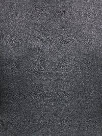 Gros plan sur un tissu gris foncé avec une texture fine, densément tissée et de subtiles taches plus claires réparties sur toute la surface.