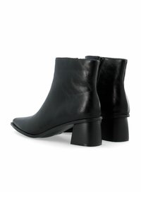 Bottines en cuir noir avec un bout pointu et un talon épais. Texture lisse, design minimaliste, avec une fermeture éclair à l'arrière.