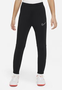 Schwarze Sporthose mit elastischem Bund, taillierter Form und silbernem Nike-Logo. Mit Kniefelgen und glatter Stofftextur.