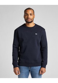 Mörkblå sweatshirt i bomull, med rund halsringning och ribbade ärmslut, med en liten vit logotyp på bröstet.