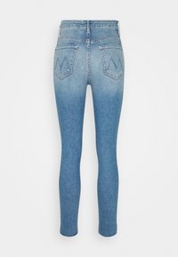 Jeans skinny de tiro alto, de un azul claro deslavado, mostrados desde la parte de atrás, con dos bolsillos traseros que presentan sutiles diseños de "M" bordados.