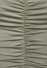 Tessuto arricciato in verde oliva tenue, con pieghe orizzontali che creano texture sulla superficie, e una finitura liscia, simile alla satin.
