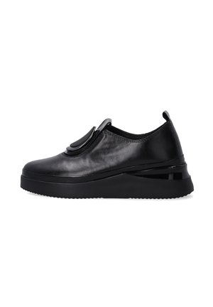 Czarne skórzane sneakersy wsuwane z grubą podeszwą, zaokrąglonym noskiem i dużym okrągłym elementem dekoracyjnym na górze.