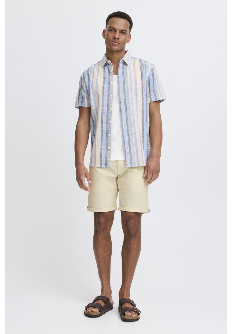 Short-sleeve button-up shirt with blue, pink, and yellow stripes; paired with beige shorts. Brown sandals complete the look.