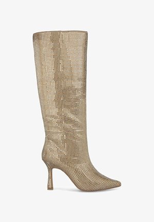 Bottes dorées métalliques arrivant jusqu'au genou, avec un motif en grille texturé, un bout pointu et un talon haut fin. Fabriquées en matériau flexible.