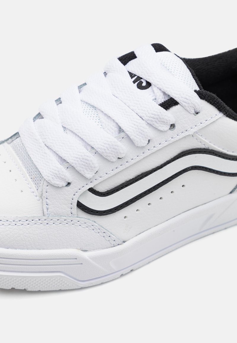 Sneaker bianco con pelle texturizzata e pannelli in rete. Presenta accenti neri, lacci bianchi piatti e una suola in gomma con battistrada a motivo.