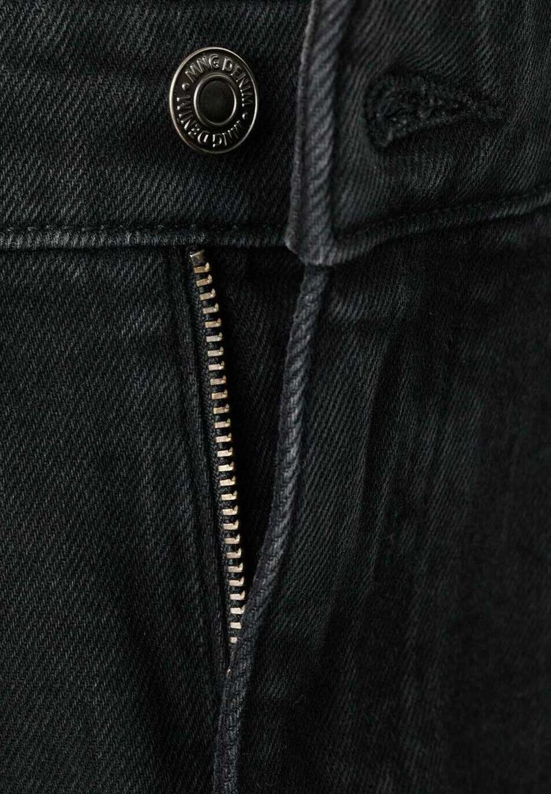 Pantalon en denim noir avec une fermeture éclair métallique, une fermeture à bouton et un tissu subtilement texturé. Détails de couture visibles le long des bords.