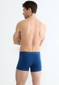 I boxer in cotone blu presentano un morbido elastico con lettering di marca. Il tessuto ha una consistenza liscia e una vestibilità aderente.