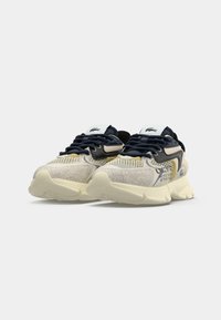 Scarpe da ginnastica beige e blu navy con pannelli in rete, dettagli in suede testurizzato, suole spesse e ammortizzate, e logo sulla linguetta e sul lato.