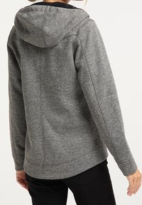 Hoodie gris en tissu doux et texturé avec une coupe ajustée, comportant une capuche à cordon et des coutures latérales pour un ajustement moderne.