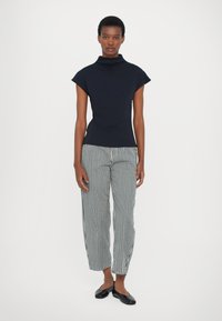 Blusa de cuello alto en color navy con mangas cortas, combinada con pantalones a rayas en blanco y negro. Los pantalones tienen un corte holgado y una cintura elástica.
