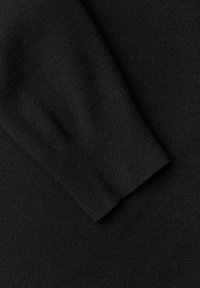 Gros plan sur un pull noir en tissu doux, avec un poignet côtelé, une texture lisse et une couleur uniforme sur toute la surface.