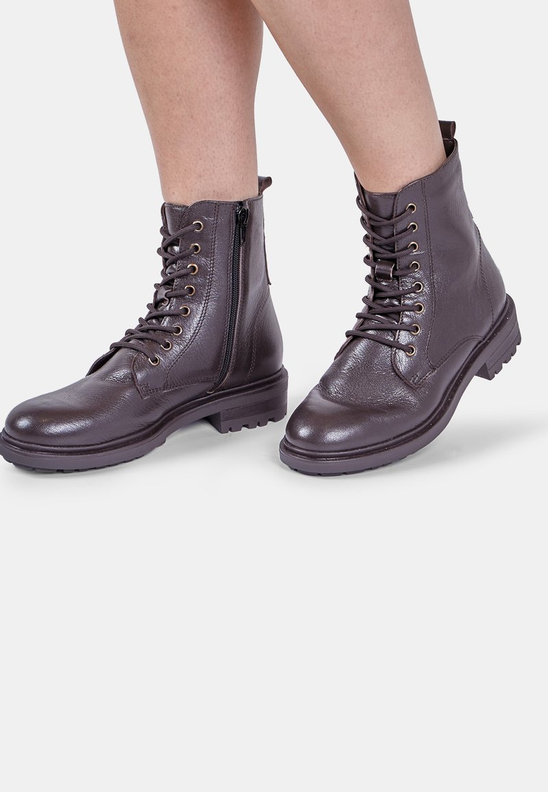 Stivali alla caviglia in pelle marrone con lacci frontali e zip laterale, finitura testurizzata e suola robusta per una buona aderenza. Occhielli dorati accentuano il design.