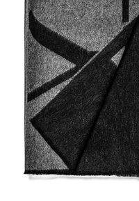 Grijze en zwarte wollen deken met een gradientpatroon, voorzien van een zachte textuur en franjes aan de randen, deels gevouwen om verschillende lagen te tonen.