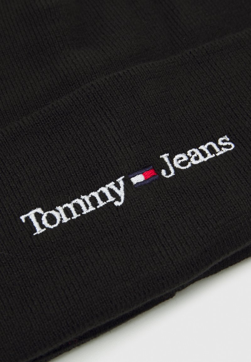 Czarna dziana czapka beanie z białym haftowanym logo „Tommy Jeans” z akcentami w kolorach czerwonym, białym i niebieskim. Miękka tekstura i elastyczny fason.
