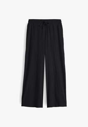 Black wide-leg pants made of textured fabric with an elastic waistband and adjustable drawstring. Features a relaxed fit and no pockets.
