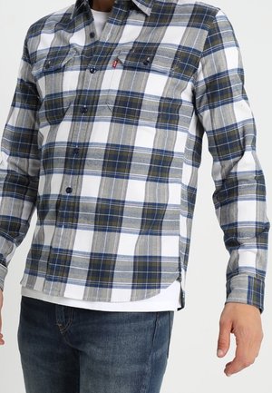 Camicia a quadri in grigio, blu e bianco. Design con bottoni e due tasche sul petto, orlo curvo. Realizzata in tessuto tessuto. Maniche lunghe.