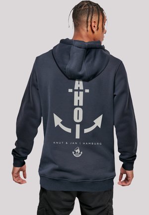 Navy blue hoodie features an anchor design with "AHOI" text and arrows on the back. Cotton material with ribbed cuffs and hem.