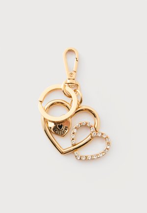 Llavero dorado con tres colgantes en forma de corazón, uno grabado con "Moschino" y otro adornado con pequeños cristales transparentes.