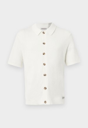 Maglia bianca a maniche corte con motivo a trama, colletto e una fila verticale di sette bottoni marroni sul davanti.