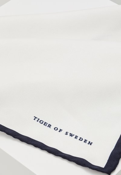 Vit scarf med marinblå kant och scalloped edge. Broderad "TIGER OF SWEDEN" i marinblått nära kanten. Texturerad tyg.