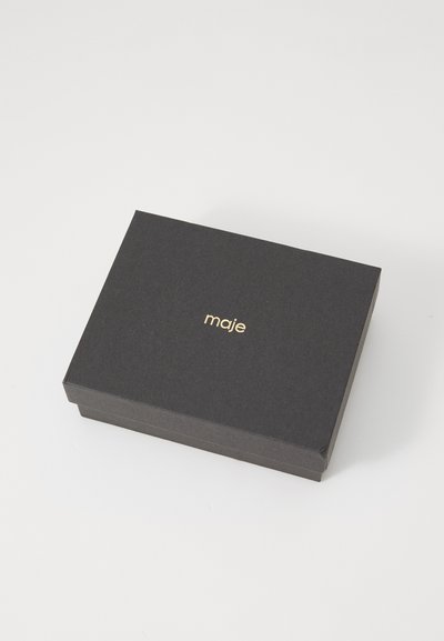 Schwarze rechteckige Box mit glatter Textur und einem goldenen Logo "maje", das zentriert auf der Oberseite platziert ist. Keine zusätzlichen Muster oder Beschläge sichtbar.