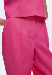 Roze linnen ensemble met een cropped top en high-waisted broek, die een zachte textuur en op maat gemaakt ontwerp met minimale naden toont.