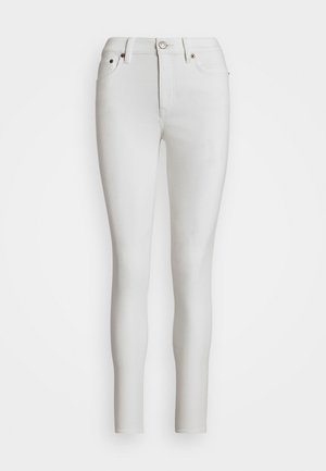 Jean slim blanc avec fermeture avant à bouton et zip, passants de ceinture et design cinq poches, présenté sur un fond uni.