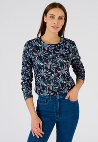 Camicia a maniche lunghe blu navy con motivo floreale in azzurro chiaro e rosa. Tessuto di cotone morbido, colletto tondo, vestibilità slim, abbinata a jeans blu.