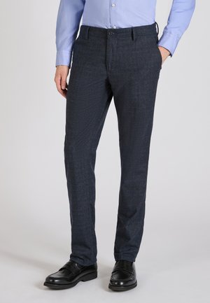 Maßgeschneiderte dunkelblaue Hose mit einem strukturierten Muster, ausgestattet mit einem Knopfverschluss, Gürtelschlaufen und Seitentaschen, kombiniert mit schwarzen Lederschuhen.