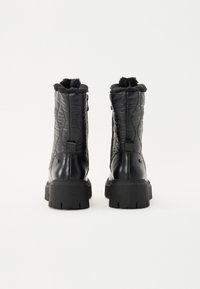 Bottes mi-mollet matelassées noires avec doublure en fausse fourrure, dotées d'une semelle en caoutchouc texturé, d'une languette au dos et d'une fermeture éclair latérale.