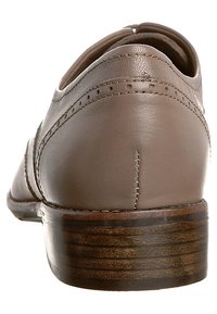 Chaussure en cuir marron à talon bas, forme arrondie, détails de couture visibles et texture lisse ; semelle en bois avec lignes horizontales.
