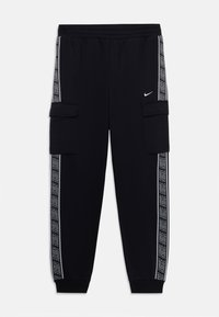 Juodos Nike treninginės kelnės su elastinga juosmele, šoninėmis kišenėmis ir kontrastingomis šoninėmis juostomis, kurių rašte kartojamas prekės ženklas. Medvilnės mišinio audinys.