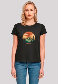 Black short-sleeve t-shirt featuring a circular graphic of mountains and trees in orange, green, and beige tones, with a relaxed fit.