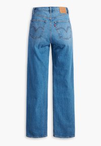 Jean en denim bleu à jambe droite vu de dos avec deux poches arrière, des passants de ceinture et une étiquette en cuir de marque sur la ceinture.