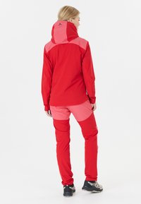 Veste imperméable rouge avec des accents roses. Comprend une capuche, des manches longues et un pantalon rouge assorti avec des patchs roses. Complété par des bottes robustes.