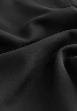 Tela negra con una textura suave y mate, que muestra pliegues y arrugas sutiles, destacando su naturaleza ligera y flexible.