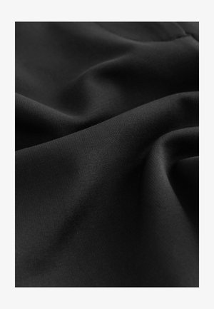 Tela negra con una textura suave y mate, que muestra pliegues y arrugas sutiles, destacando su naturaleza ligera y flexible.