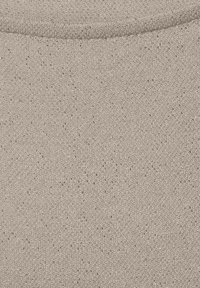 Ljus beige tyg med en strukturerad väv och små mörka prickar, som har en mjuk, slät textur och en lätt lyster vid kanterna.