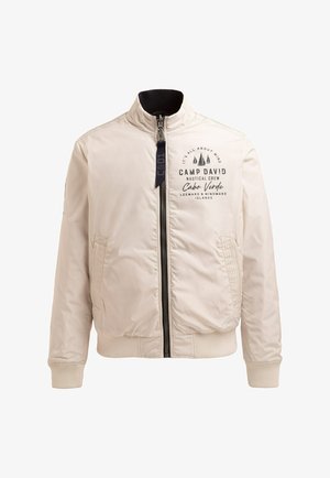 Light beige bomber jacket with a ribbed collar and cuffs. Features a front zipper, side pockets, and printed branding on the chest.