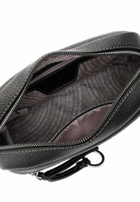 Interno di una borsa in pelle nera testurizzata, caratterizzato da una fodera grigia con testo ripetuto, una chiusura con zip e un portachiavi attaccato.