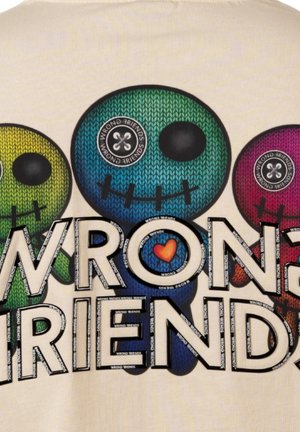 Camiseta gráfica colorida que presenta tres calaveras de dibujos animados con acentos de costura, etiquetadas como "AMIGOS INCORRECTOS" en letras grandes, sobre un fondo claro.